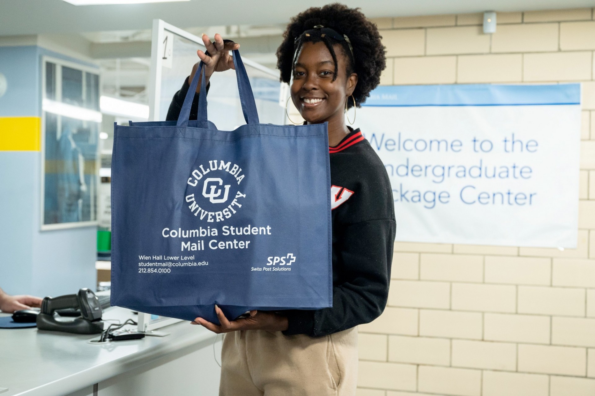 A person holds up a Columbia Student Mail Center bag at the Undergraduate Package Center.