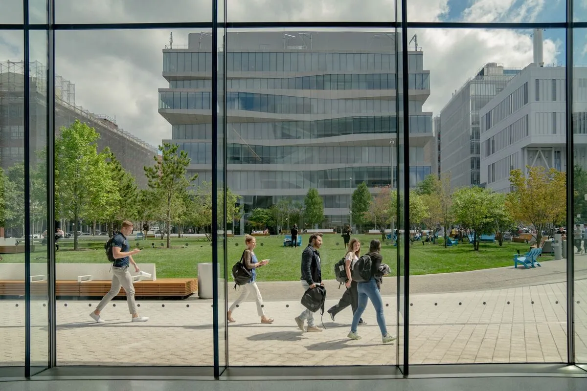 A view from inside Henry R. Kravis Hall looking out to The Square and David Geffen Hall, with students walking around.