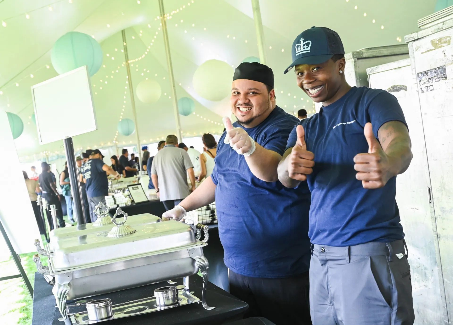 Two dining staff members give the camera a "thumbs up" at New Student Orientation dining service.