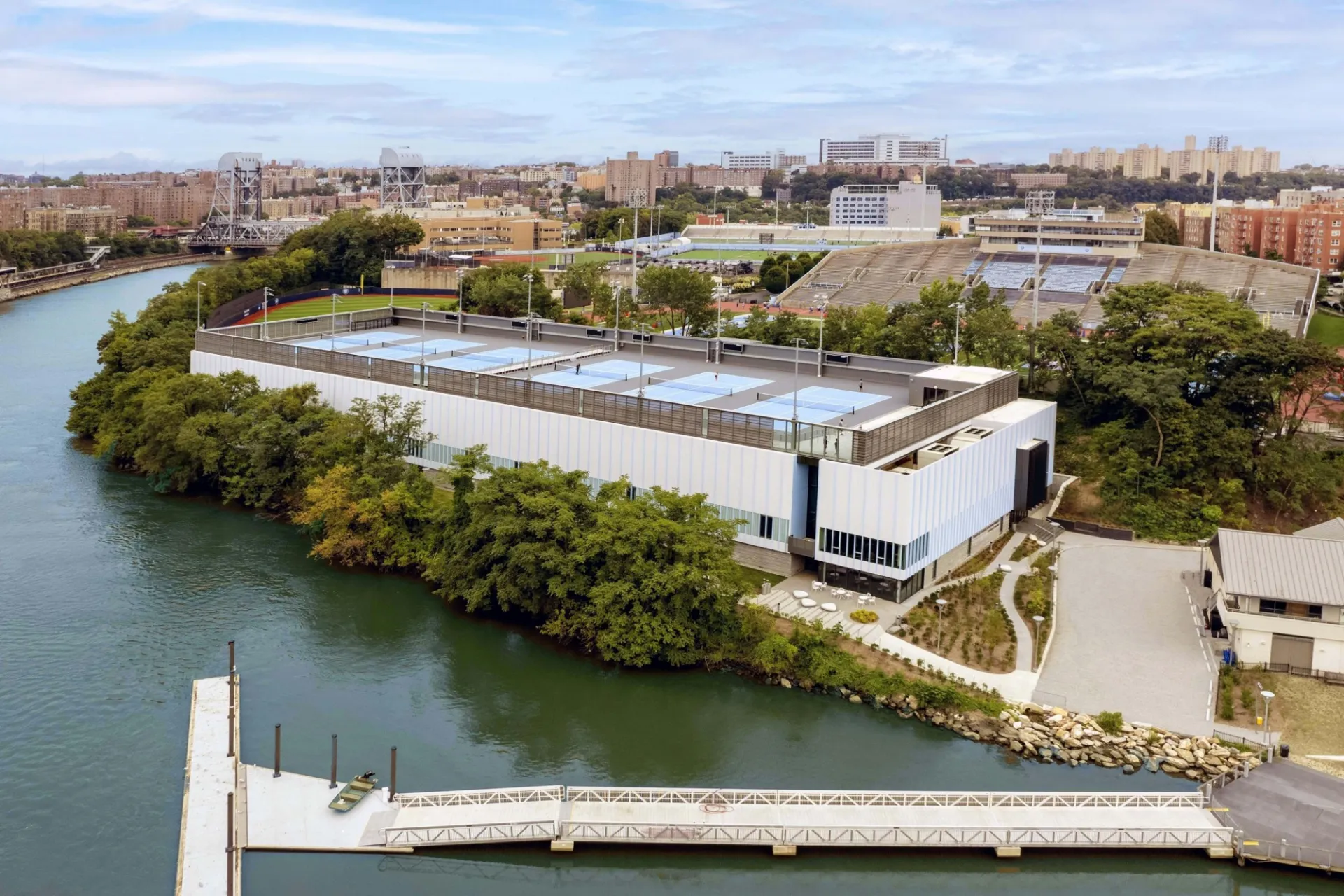 An aerial view of the newly constructed tennis center at Baker Athletics Complex next to a river.